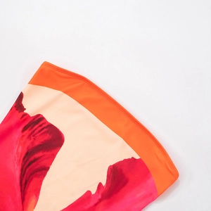 Detail of floral print skirt with elastic orange waistband and vibrant flower patterns