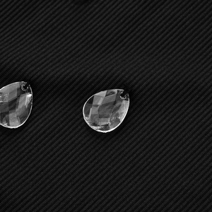 Detailed macro view of black ribbed fabric with elegant crystal water drop pendants