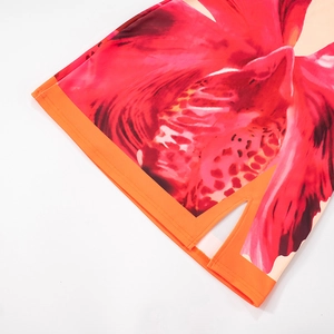 Detail of red floral print skirt featuring orange contrast hem and side slit design