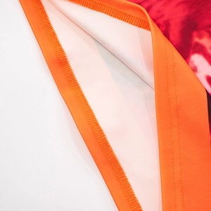 Macro shot of vibrant floral dye fabric with orange hem binding and durable twin-needle stitching