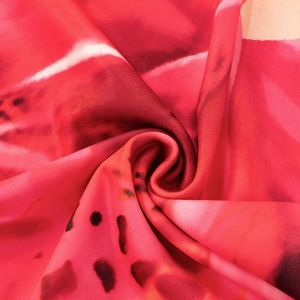 Detailed close-up showing the red and pink floral fabric texture of the bodycon dress
