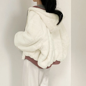 Detail of white plush hooded jacket featuring pink patchwork hem and oversized design