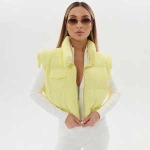 Women's pale yellow cropped puffer vest with stand collar and zipper on model
