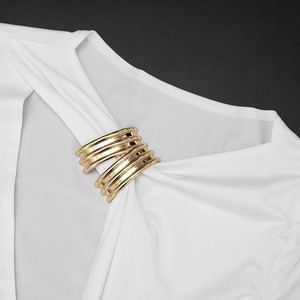Macro detail of a multi-layer gold alloy scarf ring on white fabric background