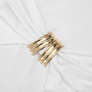 Detail view of a polished gold multi-layer ring scarf buckle on textured white fabric
