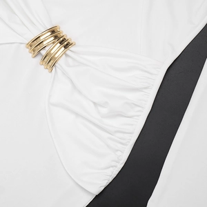 Detailed close-up of golden metallic rings on a white pleated dress with layered drapes
