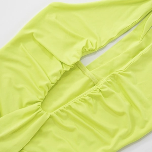 Detail of lime green dress featuring ruching craftsmanship and side cutout design