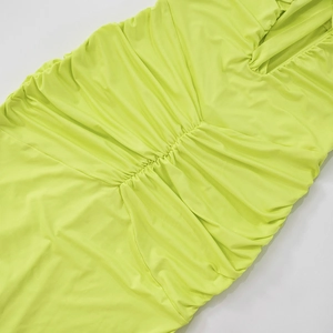 Detail of neon green ruched fabric on halter dress showing texture and stitching