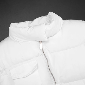 Detailed close-up of a white quilted vest featuring a metal zipper and cargo pocket