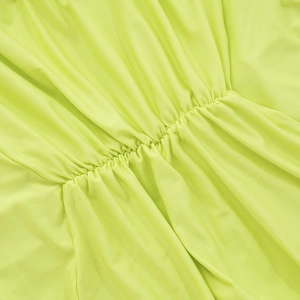 Detailed view of neon green halter dress showing elastic shirred waist and fabric texture