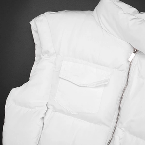 Detail of white puffer vest showing stand collar metal zipper and flap pocket design