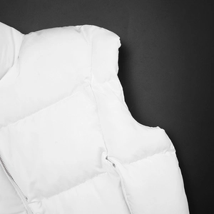 Detail shot of white quilted puffer vest featuring smooth waterproof fabric and silver zipper