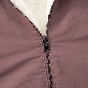 Detail of dark pink quilted fabric with thick white faux fur lining and metal zipper