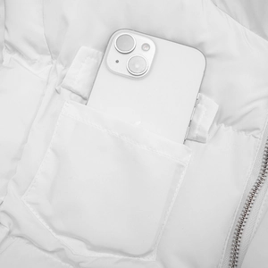Detail of white quilted vest showing inner pocket with metal zipper and phone storage