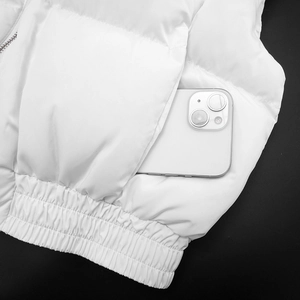 Detail of white puffer vest showing functional side pocket with a smartphone inside