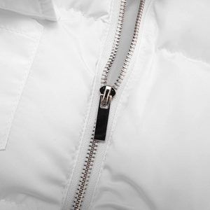 Detailed macro view of white quilted padded vest featuring a premium silver metal zipper