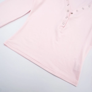 Detail of light pink henley top showing silver metal ring buttons and soft knit texture