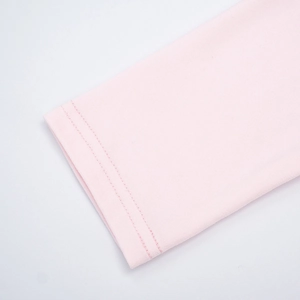 Detailed close-up of light pink knitted fabric sleeve with high-quality double stitching