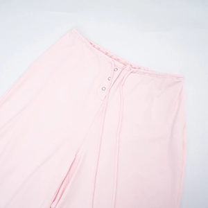 Detail of light pink knit joggers featuring drawstring waist and decorative silver buttons