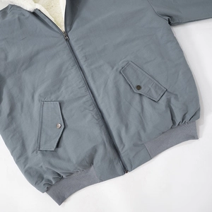 Detail of blue-grey jacket featuring sherpa lining, metal zipper and cargo pockets