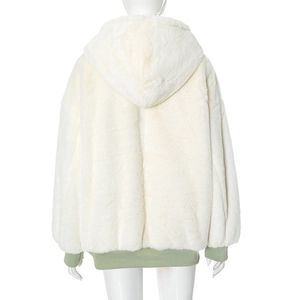 Macro view of plush cream faux fur texture with ribbed green cuff details on a hooded jacket
