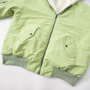 Detailed view of light green bomber jacket with warm white fleece lining and ribbed hem
