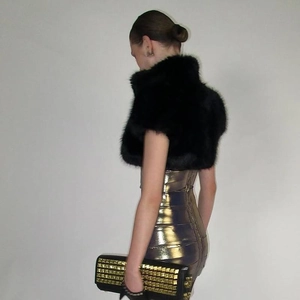 Seitenansicht von Kunstpelz-Achselzucken und Metallic-Kleid mit goldener Clutch