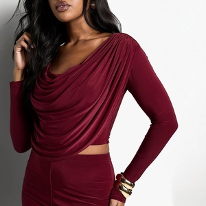 Detail of burgundy long sleeve top featuring a cowl neck and shimmering elastic knit fabric