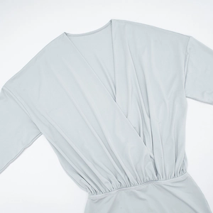 Detail of light gray wrap V-neck dress featuring elegant pleated waist and long batwing sleeves