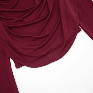 Detailed close-up of burgundy draped fabric and clean double-needle hem on sleeve cuff