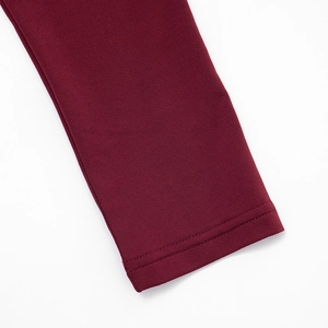 Macro shot of burgundy knit fabric detailing fine double-needle stitching on hem