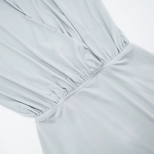 Detail view of high-waist pleats and drape texture on a light grey batwing dress