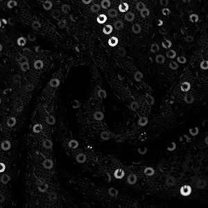 Macro shot of shimmering black sequins sewn onto mesh fabric for an elegant evening dress