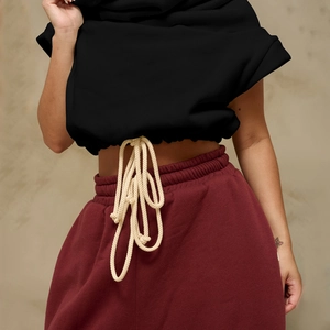 Detail of waist area showing elastic drawstring on burgundy pants with black cropped hoodie