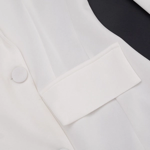 Detail of white blazer dress featuring fabric covered button and flap pocket stitching