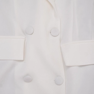 Close-up of double-breasted white blazer dress with fabric-covered buttons and pocket detail