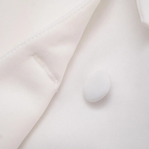 Close-up of white woven dress fabric with a fabric-covered button and stitched buttonhole
