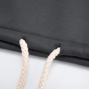Macro detail of charcoal grey hoodie fabric featuring thick cream woven drawstrings