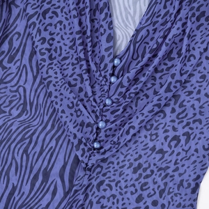 Detail of V-neckline with blue pearl buttons on purple leopard print animal pattern dress