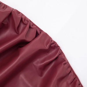 Détail de la texture froncée en similicuir bordeaux sur cette robe moulante ajustée