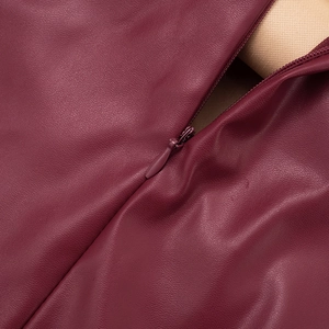 Gros plan sur la fermeture éclair invisible d'une robe courte en simili cuir bordeaux
