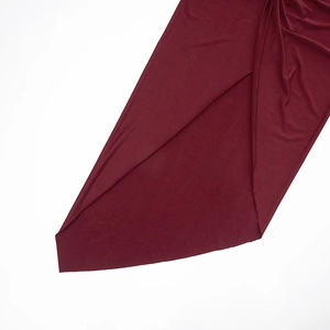 Detail of burgundy knitted dress showing soft fabric texture and elegant slit hemline