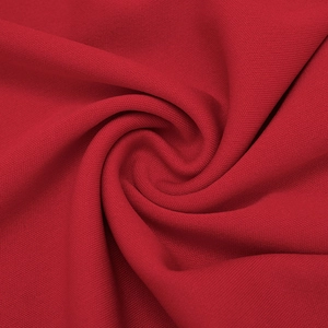 Close-up of bright red knitted fabric showing soft mesh bird-eye texture and elasticity