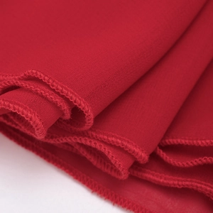 Macro detail of dark red chiffon fabric showing fine hem stitching and soft drape