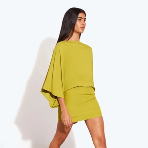 Détail de la robe courte vert moutarde avec des manches cape élégantes et une coupe ajustée