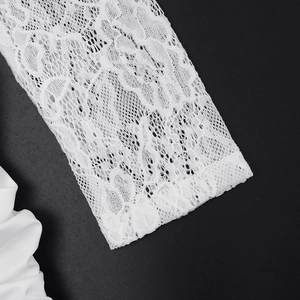 Detailaufnahme der weißen Spitzenmanschette und des Plisseestoffs am Langarmkleid