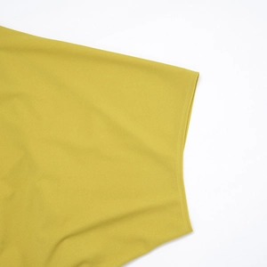 Gros plan d'une robe jaune moutarde montrant les détails de couture à double aiguille