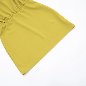 Détail d'une robe jaune moutarde montrant le tissu plissé et la finition de l'ourlet