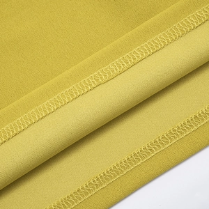 Gros plan sur tissu jaune moutarde montrant les coutures surjetées et la texture tissée