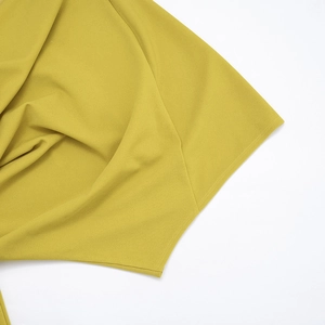 Gros plan de la double couture sur l'ourlet d'une robe courte jaune moutarde élégante